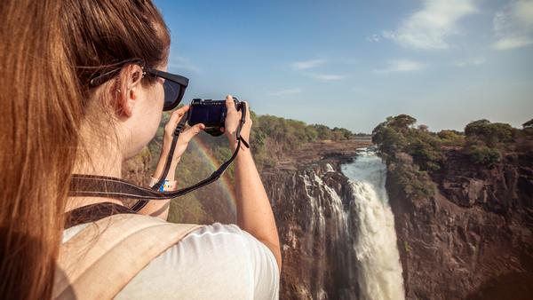 tourist taking photo of Victoria Falls in Zimbabwe