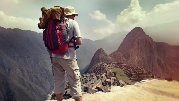 male hiker carrying a backpack gazes at the ruins on Machu Picchu tour