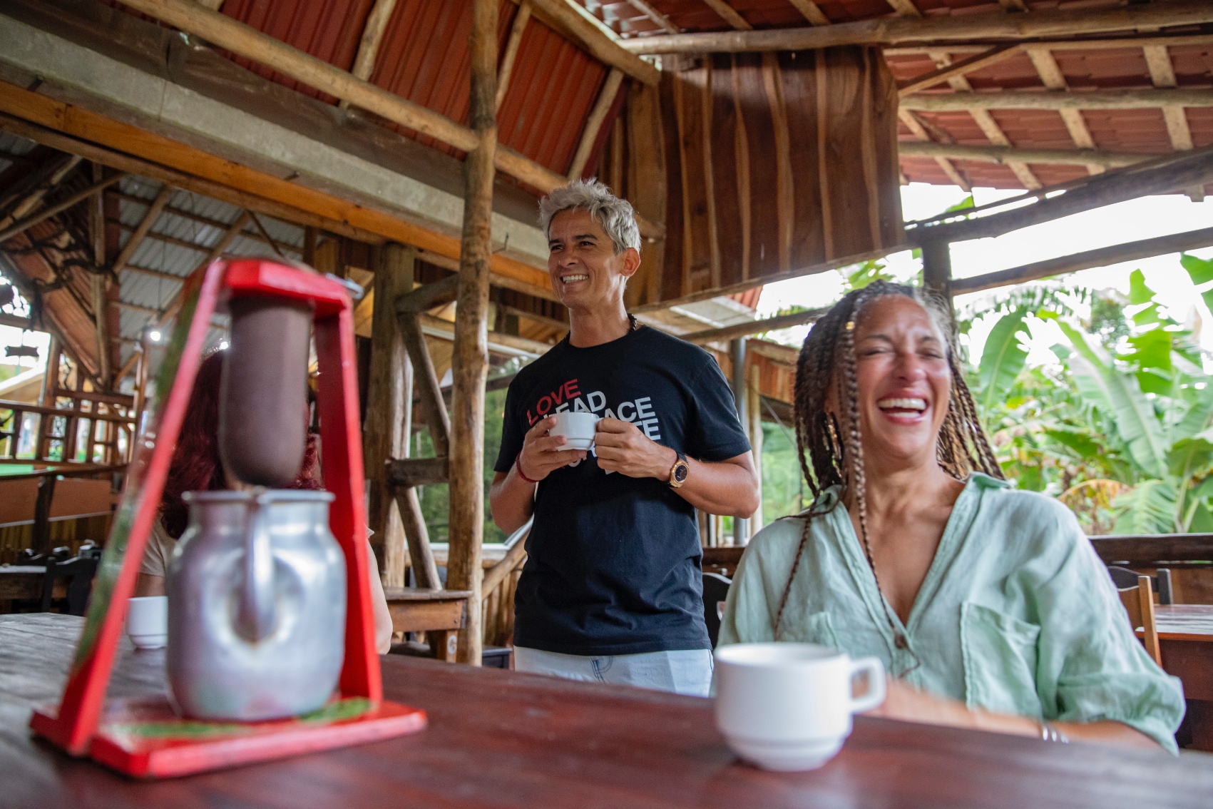 a solo female traveller laughs along with her local guide at a coffee farm