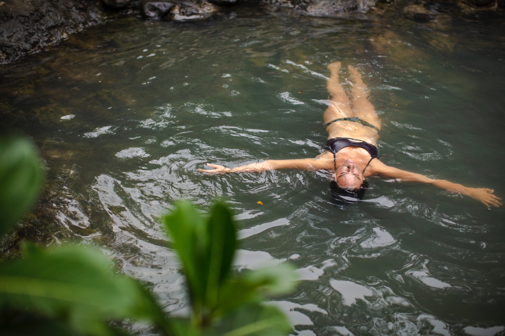 a solo female traveller floats peacefully in Costa Rica hot springs