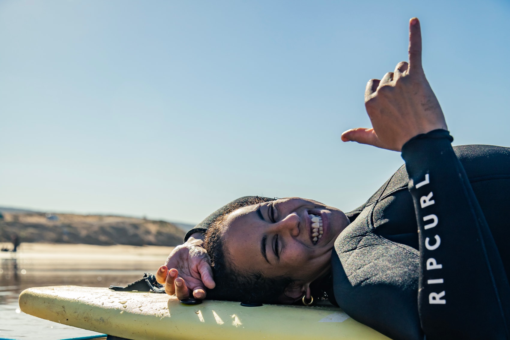 A traveller learning to surf in Taghazout throws a shaka