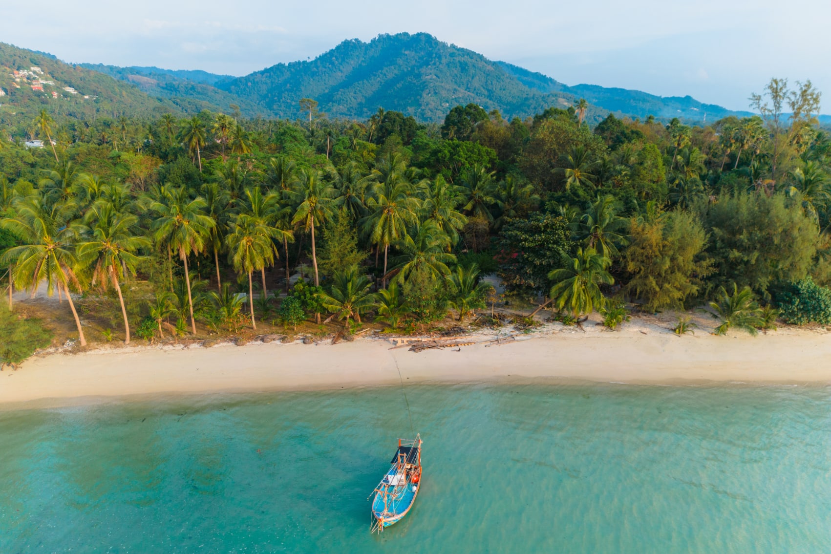 a traditional boat floats in the crystalline waters off Koh Samui island, Thailand