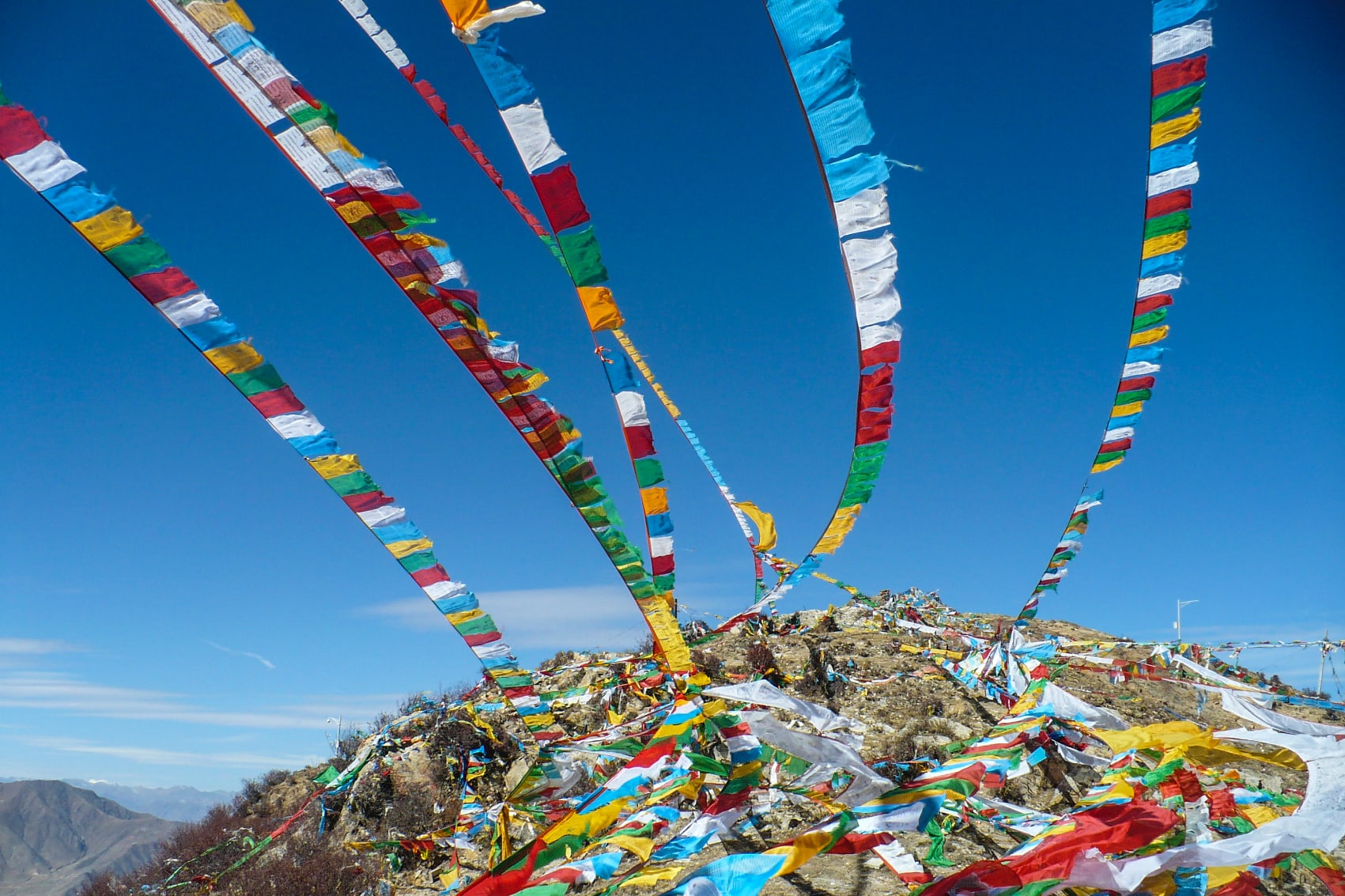 colourful Tibetan prayer flags stream from atop Himalayan mountains