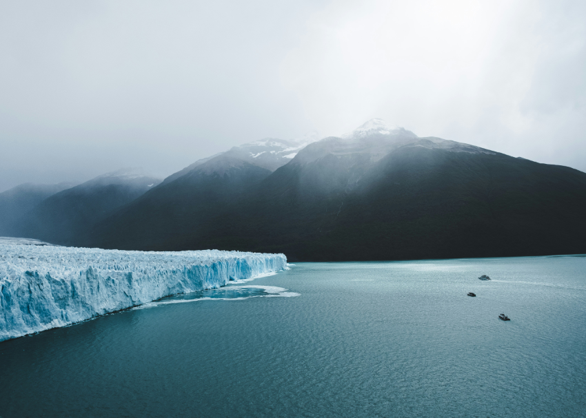 a moody display of the Perito Moreno Glacier's blue ice as boats look on in Patagonia