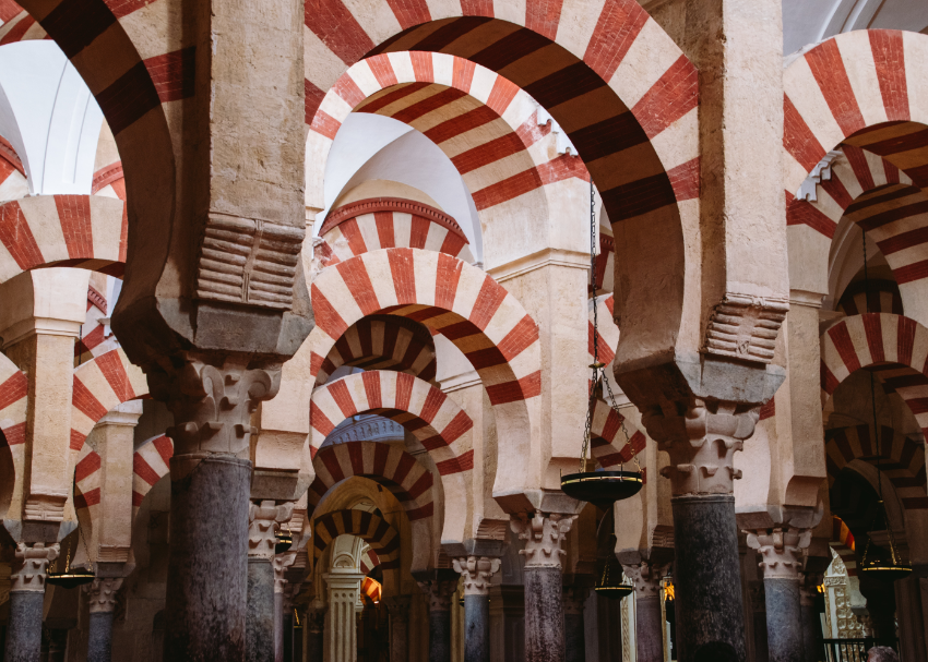 An interior look at the many overhead striped terracota-coloured arches at Mezquita-Catedral de Córdoba, a historic mosque and cathedral