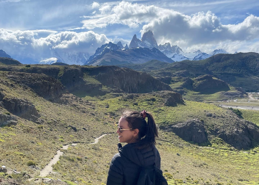 famed jagged peaks touch the clouds in the distance as writer Jessica Moy smiles at the walk ahead