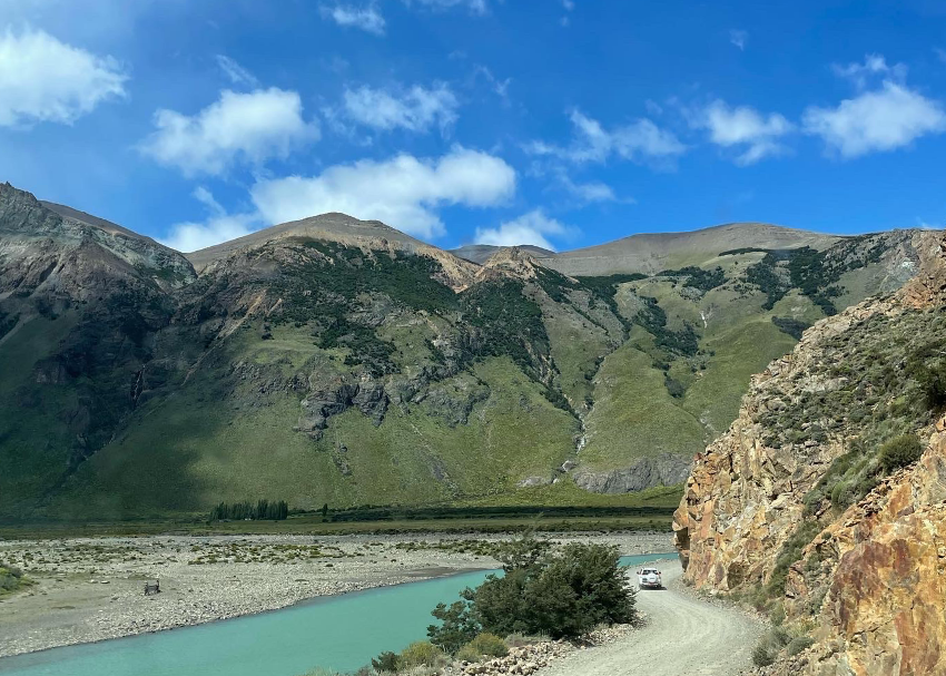 pristine green-sided cliff faces flank a turquoise blue river bed and roadway