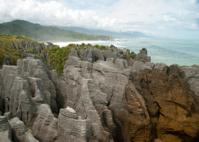 overlooking the pancake stack rock formations of Punakaiki, New Zealand with the lapping ocean waves in the distance