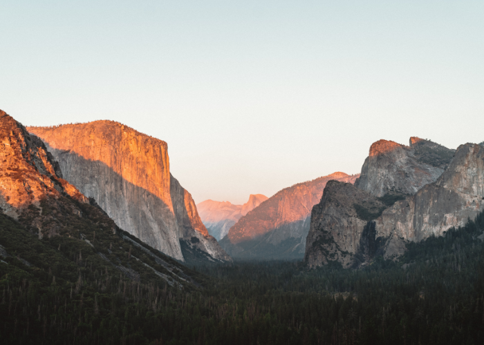 a peachy pink moment as the setting sun lights up the granite monoliths of El Capitan and Half Dome in Yosemite National Park